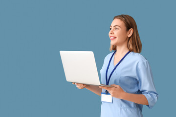 Wall Mural - Female intern with laptop on blue background