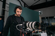 © Anna - Director of photography with a camera in his hands on the set. Professional videographer at work on filming a movie