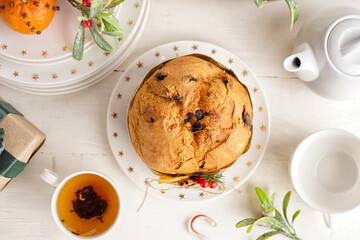 Wall Mural - Plate with tasty Panettone, cup of tea and Christmas decor on white wooden table, top view