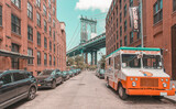 Fototapeta Nowy Jork - Manhattan Bridge seen from Brooklyn in narrow alley enclosed by two brick buildings on a sunny day in Washington street in Dumbo, Brooklyn, NYC