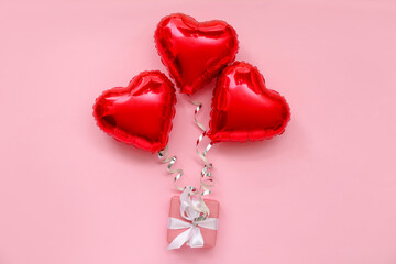 Composition with gift box and heart shaped balloons on pink background. Valentine's Day celebration