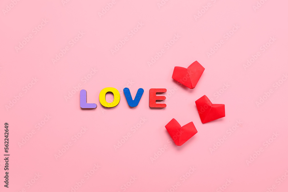Word LOVE with paper hearts on pink background. Valentine's Day celebration