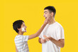 © Pixel-Shot - Man and his little son with shaving foam against yellow background