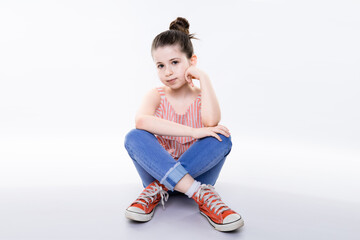 portrait of young adorable girl sit on floor on ground isolated on white with little joyful smile at camera