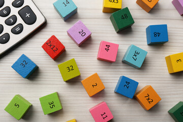 Wall Mural - Colorful cubes with numbers and multiplications near calculator on white wooden table, flat lay