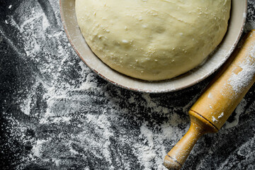 Poster - Flour background. The dough in a bowl with a rolling pin.