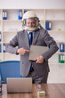 © Elnur - Old male employee wearing spacesuit in the office