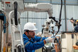 © APchanel - Engineer factory industry wearing safety uniform work and checking system of the welding robots for welding steel electrical control system by laptop robot automate for industry manufacture concept.
