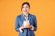 Photo of young Asian businesswoman holding piggy bank on background