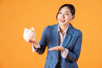 Wall Mural - Photo of young Asian businesswoman holding piggy bank on background