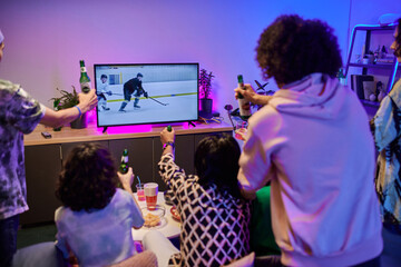 Wall Mural - Backs of youthful friends with bottles of beer gathered in front of tv set celebrating victory of their favorite hockey team at home party