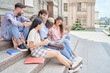 © yurolaitsalbert - multi-racial group of students sitting on the steps of the campus.