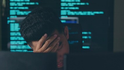 Young Asian man, developer programmer, software engineer, IT support, working hard at night overtime on computer to check coding in bugging system and running program fail and feeling stress.