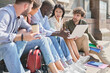 © yurolaitsalbert - multicultural team of students is chatting on the steps of the campus.