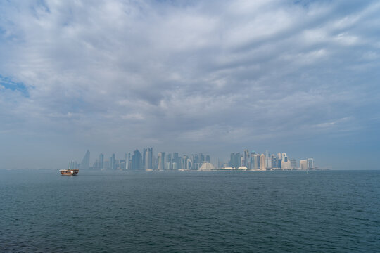 Wall Mural - A dhow returns to harbor in Doha, Qatar, with the city's modern skyline in the background.