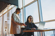 © DSMT - Two business women are looking for something in a laptop. Concept of business cooperation and teamwork. Young smiling women at the desk in the office. Modern successful people