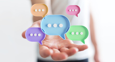 Wall Mural - Businessman using digital speech bubbles talk icons. Minimal conversation or social media messages floating over user hand. 3D rendering