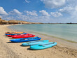 Colored windsurfing boards and canoes lie on the sea beach. Active recreation.
