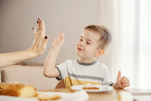 A Little Boy Is Eating His Healthy Breakfast And Giving High Five To His Mom.