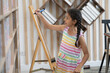 © Nassorn - Young girl student standing in classroom writing on a whiteboard. Portrait of happy Asian schoolgirl kid holding marker pen write on blank whiteboard. Child and elementary school education lifestyle.