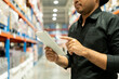 © Patcharanan - Warehouse worker wearing a hat and black shirt hands holding tablet check stock on tall shelves in warehouse storage. Asian auditor or staff work looking up stocktaking inventory in warehouse store.