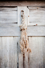 A Rustic Door Adorned With A Knotted Rope