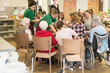 © Cavan Images - Nursing staff with senior women and girls preparing food at rest home