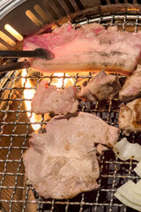 Wall Mural - Grilling pork belly meat on a round BBQ net in restaurant for eating.