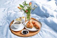 Happy Morning With Breakfast In Bed, Flowers, Croissant, Coffee And More On A Tray On Blue White Linen At Birthday, Valentines Or Mothers Day, Copy Space, Selected Soft Focus