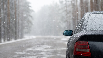 A car on the road in a snowfall, winter pine forest. Copy space