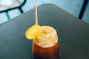 Orange coffee concept, close-up of a glass of orange coffee in the cafe. Coffee mixed with orange juice.