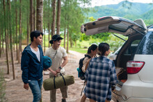 Group Of Asian People Friends Enjoy Outdoor Lifestyle Road Trip And Camping Together On Summer Holiday Travel Vacation. Man And Woman Taking Off Camping Supplies From Car Trunk At Natural Park.