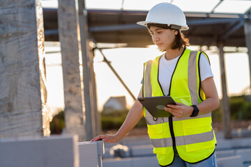 Wall Mural - Civil Engineer women in safety suite use a digital tablet to work inspection and quality control on construction site .contractor and developer real estate concept