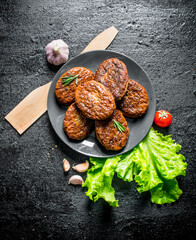 Poster - Cutlets on a plate with garlic, salad leaves and wooden spatula.