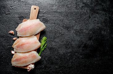 Poster - Fish fillet on a wooden stand with dill and garlic cloves.