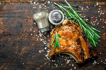 Poster - Grilled pork steak on bone with a branch of fresh rosemary.