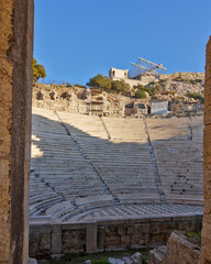 Wall Mural - The ancient Athens temple of Nike above the stands of the conservatory of Herod Atticus, as seen through an arch. Cultural travel in Athens, Greece.