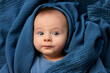 © Lisa Tichané - Portrait of newborn baby wrapped in blue blanket making funny face
