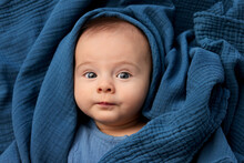 Portrait Of Newborn Baby Wrapped In Blue Blanket Making Funny Face