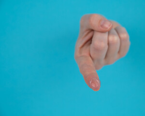 Wall Mural - A woman's hand sticks out through a blue paper background and holds a contact lens.