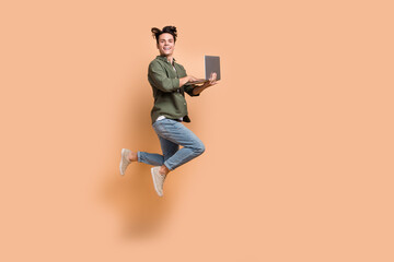 Full body length size cadre of young jumper overjoyed crazy guy hold netbook professional programmer addicted code isolated on beige color background