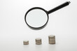 Magnifying glass with coins on gray background. Concept of banking, credit or search money.