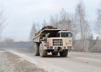 Poster - Mining truck transportation of loosened rock mass. Dolomite rock in open-pit. Haul truck in quarry. Lorry in opencast. Extraction of ore and minerals in a quarry. Excavator load ore in mining truck.