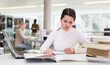 © JackF - Portrait of smiling woman with laptop and book in public library. High quality photo