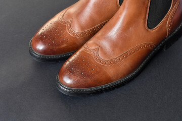 close up view light tan chelsea men boots on dark grey background