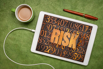 Canvas Print - risk word - letterpress wood type text against numbers on a digital tablet, flat lay with coffee, business and life concept