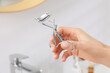 Woman with eyelash curler in bathroom, closeup. Space for text