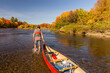 © Cavan Images - A man pulls a canoe through shallow water in a Maine river.