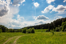 Beautiful Blue Sky With Passing Clouds Over A Bright Green Landscape Of Fields And Forests