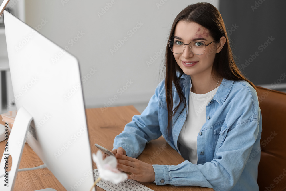 Young woman using mobile phone at table in office